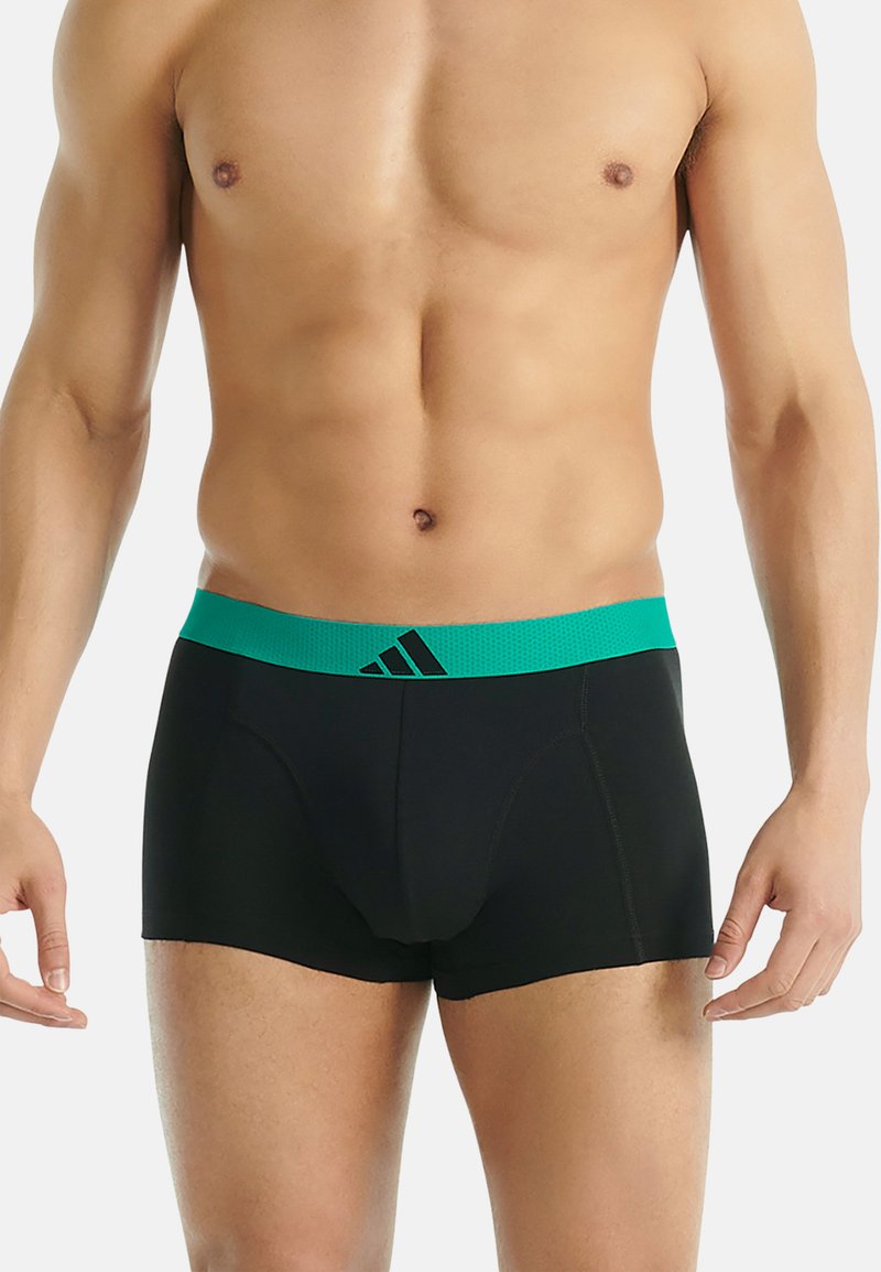 Svarta boxershorts med en åtsittande design, med en grön elastisk midja med ett texturerat mönster och en Adidas-logotyp.