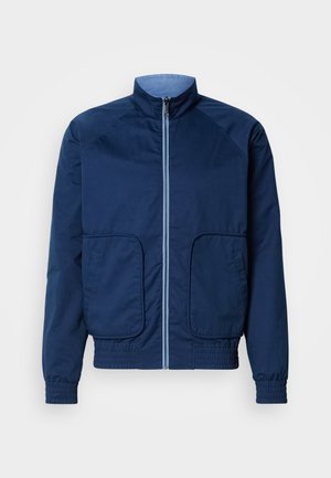 Marineblauwe lichtgewicht jas met een hoge kraag, ritssluiting, twee voorzakken en elastische manchetten en zoom. Gladde textuur, casual ontwerp.