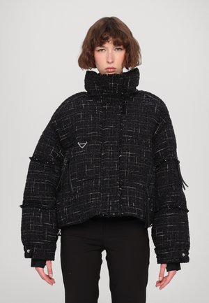 Zwarte cropped jacket van textuurgeweven stof. Heeft een hoge kraag, ritszakken en een opvallend geometrisch patroon.