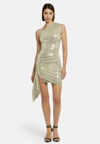 Robe courte en sequins dorés avec une épaule asymétrique, fente sur le côté et tissu texturé ; coupe élégante qui accentue la silhouette.