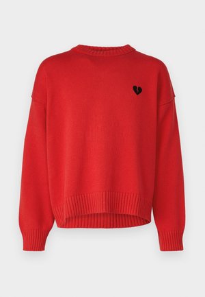 Czerwony sweter dzianinowy z prążkowanymi mankietami i dołem, z małym czarnym emblematem złamanego serca na lewej piersi.