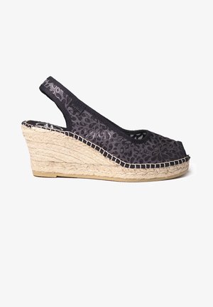 Crne espadrile s wedge petom, s gornjim dijelom od uzorkovane tkanine, otvorenim nožnim prstima i potplatom obavijenim jutom. Sadrži dizajn s remenom za podršku.