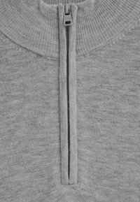 Grau zipfelpullover mit hohem Kragen. Weiche Textur, gerippter Kragen und Reißverschlussdetail vorne. Einfaches Strickmuster durchgehend.