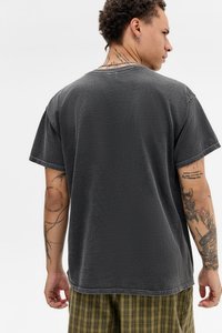 Szürke pamut Póló laza szabással és rövid ujjakkal, texturált felülettel és varrott szegéssel. Látható tetoválások a karon.