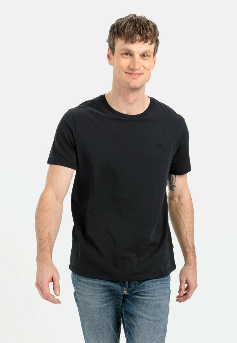 Sort bomulds t-shirt med rund hals, korte ærmer og et diskret logo. Kombineret med blå denim jeans. Blød tekstur, tætsiddende design.