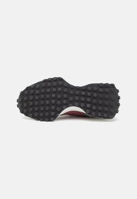 Černá kaučuková podrážka s kulatými vzory pro trakci, tvarovaná forma a různá tloušťka, s bílým mezipodešvem a červeným horním okrajem.