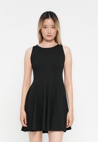 Robe noire sans manches avec un corsage ajusté et une jupe évasée, faite d'un tissu lisse, présentant un col rond et des coutures minimales.