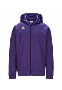 Giacca sportiva viola con cappuccio, zip completa e loghi Kappa dorati sulle spalle. Il tessuto è liscio e leggermente lucido. Due tasche laterali.