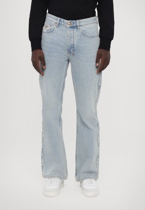 Light blue denim jeans with a straight, loose fit. Features five pockets, belt loops, and copper-tone hardware. Worn with white footwear.