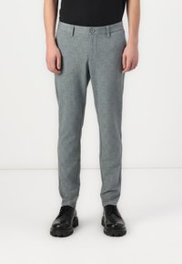 Gray patterned trousers feature a slim fit, flat front, and button closure, with side pockets and rolled cuffs, paired with black shoes.