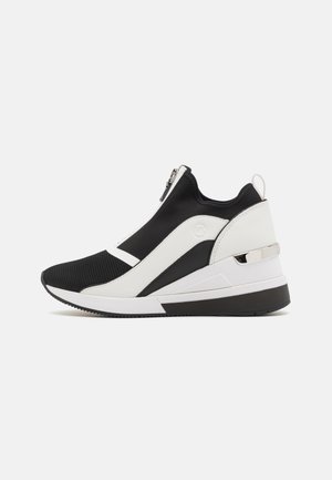 Czarno-białe buty sportowe typu slip-on z przednim zamkiem błyskawicznym, siateczkowym noskiem, pętelką do ściągania oraz grubą podeszwą z czarno-białymi detalami.