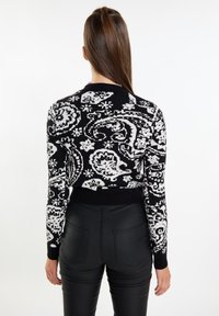 Maglione in bianco e nero con motivo paisley, polsini e orlo a costine, dal taglio corto e texture lavorata a maglia.