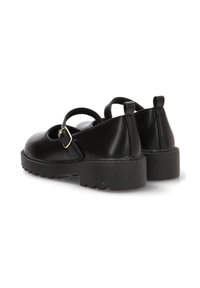 Zapatos de cuero negro con una suela gruesa, presentando dos correas y un detalle de hebilla. Punta redondeada y superficie texturizada.