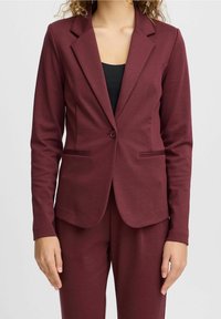 Burgundin värinen bleiseri, jossa on lovellinen kaulus, yksikköpainikekiinnitys ja kaksi etutaskua. Valmistettu sileästä, joustavasta kankaasta.