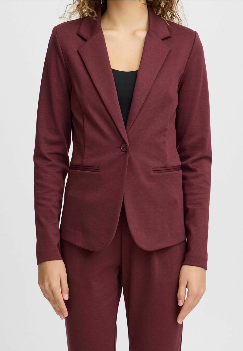 Burgundin värinen bleiseri, jossa on lovellinen kaulus, yksikköpainikekiinnitys ja kaksi etutaskua. Valmistettu sileästä, joustavasta kankaasta.