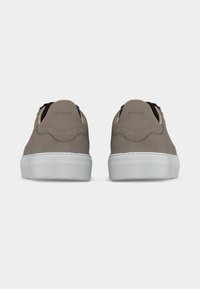 Ζευγάρι μουτζουρωτά μπλε σνίκερς με λευκές λαστιχένιες σόλες, απεικονιζόμενα από πίσω, εμφανίζοντας την επωνυμία Nubikk στις ετικέτες της φτέρνας.