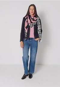 Zwarte op maat gemaakte jasje, roze top en blauwe jeans. Gecombineerd met een roze en zwart patroon sjaal en zwarte enkellaarsjes.