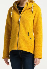 Žlutá fleecová bunda se zipem, nastavitelnou kapucí se šňůrkami, bočními kapsami a uvolněným střihem. Texturovaná látka s melírovaným vzorem.