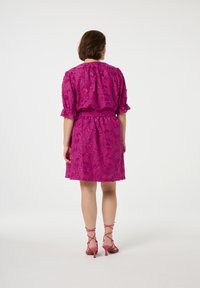 Fuchsia jurk met bloemenborduursel, korte gerimpelde mouwen, elastische taille en een uitlopende rok, gecombineerd met roze sandalen met bandjes.