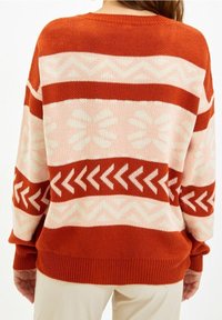 Gestrickter Pullover mit großen horizontalen Streifen in Rost, Hellrosa und Creme. Mit geometrischen Mustern sowie gerippten Bündchen und Saum.