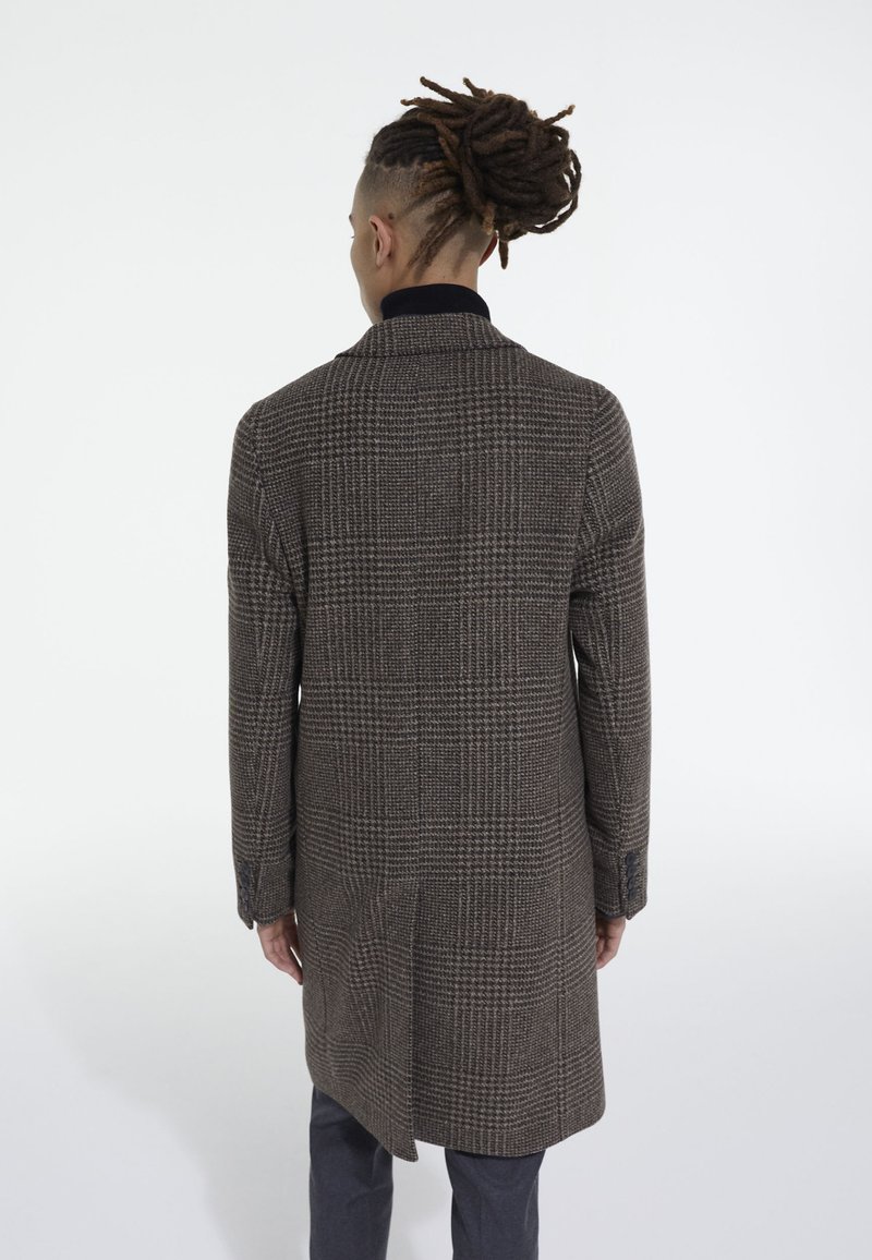 Cappotto a quadri marrone con colletto, maniche lunghe e spacchi laterali. Il tessuto ha una finitura strutturata e presenta un motivo a quadri.