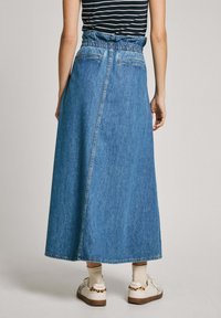 Denim maksi svārki ar elastīgu jostu, sānu kabatām un taisnu siluetu. Gaiši zila krāsa ar vieglu nodilumu un izšūtiem detaļām.