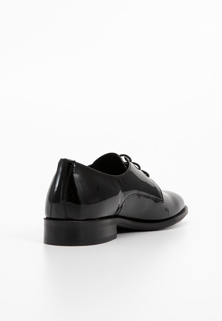 Czarne, lakierowane buty wizytowe z okrągłym noskiem, niskim obcasem i sznurowanym zapięciem. Gładka powierzchnia z akcentami w postaci przeszyć.