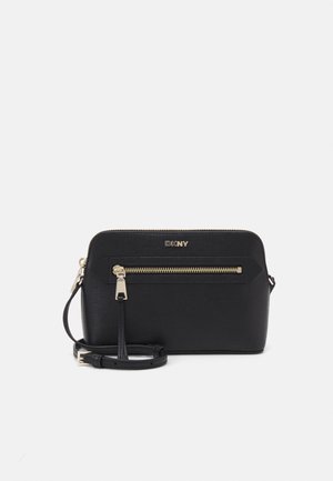 Zwarte DKNY crossbodytas met gouden ritspocket, verstelbare band en gladde textuur, afgebeeld op een witte achtergrond.