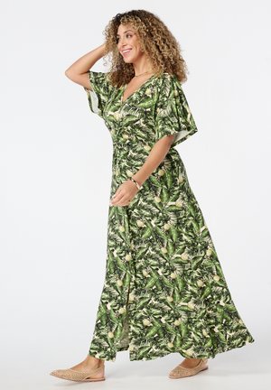 Maxi-jurk in groen met een tropische bladeren- en ananasprint. Korte mouwen, V-hals, vloeiende vorm, zachte stof en een uitsnijding aan de zijkant.