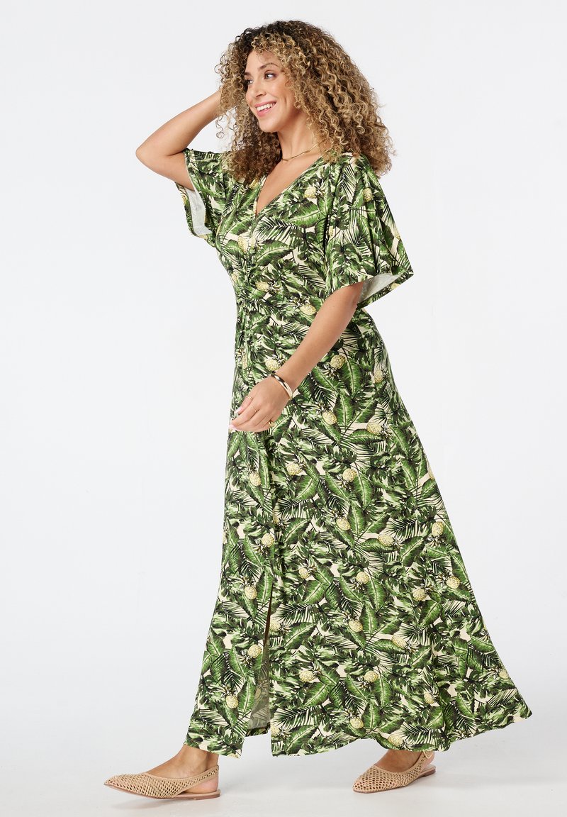 Maxi-jurk in groen met een tropische bladeren- en ananasprint. Korte mouwen, V-hals, vloeiende vorm, zachte stof en een uitsnijding aan de zijkant.