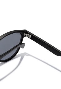 Black sunglasses with a matte finish, round lenses, flexible metal hinges, and sleek arms. Textured surface and minimalistic design.