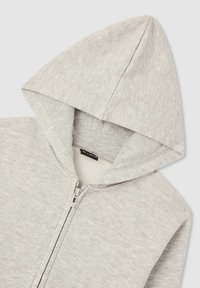 Felpa grigia chiara con chiusura a zip, cappuccio con cordino e texture morbida. Presenta una vita leggermente elastica e polsini a coste.