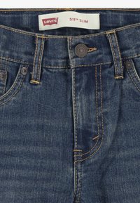 Tmavomodré deninové nohavice Levi's 511 Slim s uzatváraním na gombík a zips, viacerými vreckami a kontrastným zlatým prešívaním.