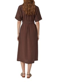 Hnědress s délkou po kolena, krátkými rukávy a opaskem v pase. Vyrobené z texturované látky, mají pohodlný střih a volnou siluetu.