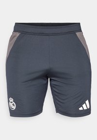 Shorts sportivi grigi con pannelli laterali neri, dotati di un logo bianco del Real Madrid su una gamba e strisce bianche Adidas sull'altra.