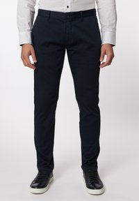 Navy Chinos aus gewebtem Stoff, im Slim Fit-Stil, mit vorderen Taschen und einem Knopfverschluss, kombiniert mit schwarzen Sneakern.