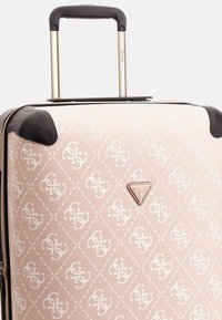 Kovaloidut laukku vaaleanpunaisena, jossa on timanttikuvio. Varustettu vedettävällä kahvalla, mustilla yksityiskohdilla ja logotunnuksella.