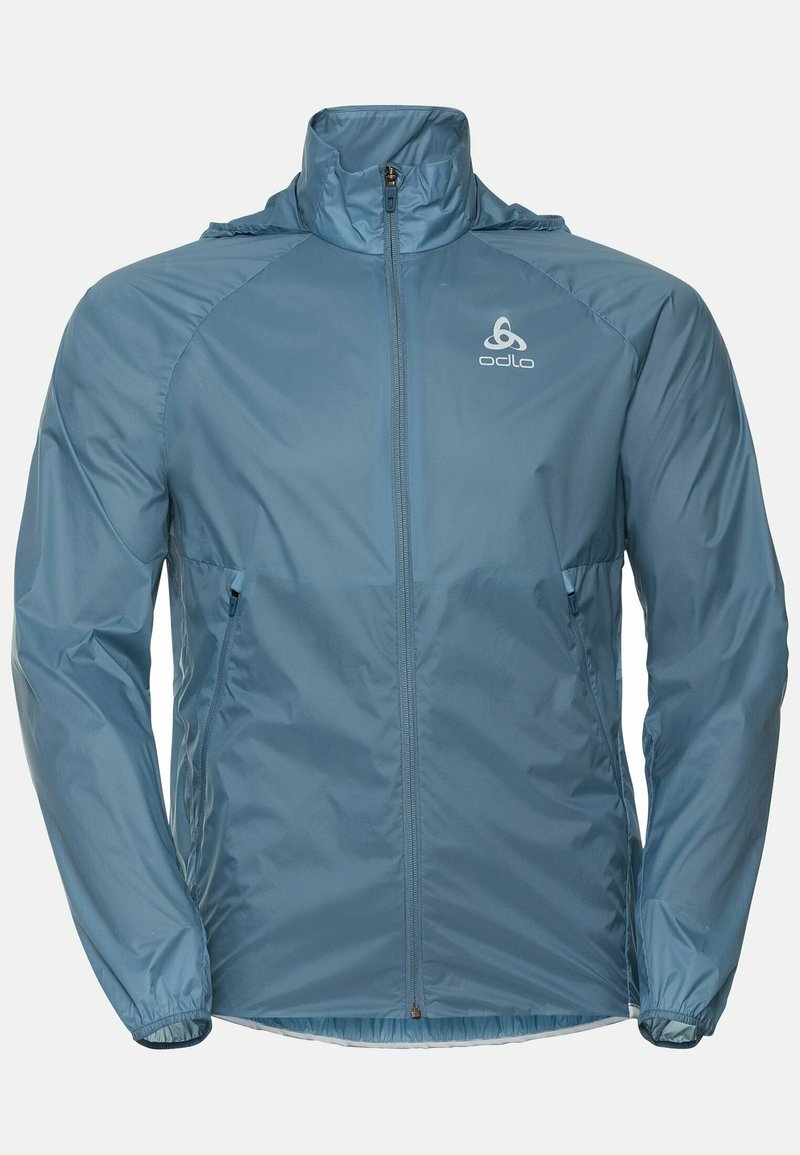 Lekkka, niebieska kurtka z wysokim kołnierzem, pełnym zamkiem błyskawicznym, elastycznymi mankietami i kieszeniami bocznymi. Posiada logo na górnej lewej części klatki piersiowej.