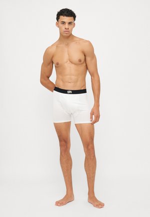 Caleçons boxers blancs avec une ceinture noire, fabriqués à partir d'un tissu lisse et extensible. La coupe est ajustée et ils ont un design classique sans motifs.