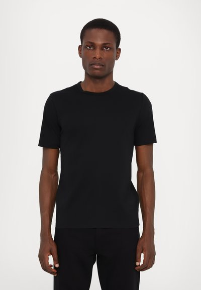 T-shirt noir à manches courtes et col ras du cou en tissu lisse. Design ajusté avec une silhouette épurée, sans motifs ni détails matériels visibles.