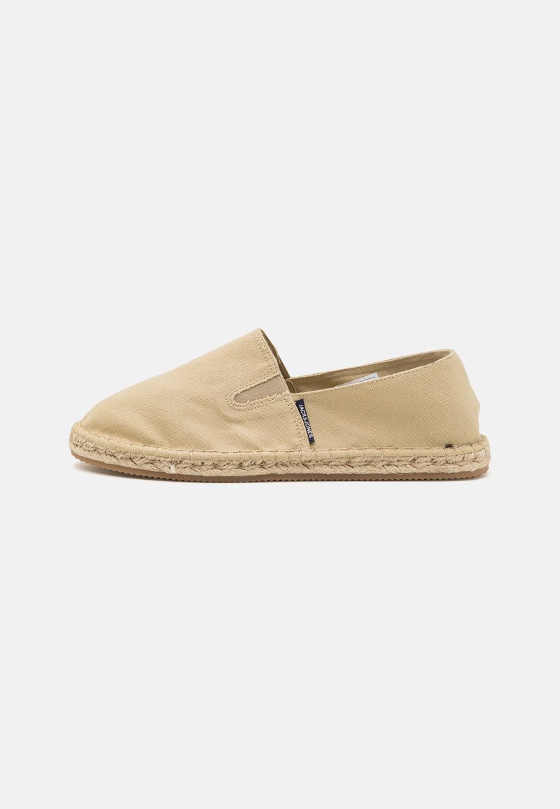Beige canvas slip-on sko med rund tå, elastiske sidelukninger og jute reb trim langs sålen. Flad og lavprofil design.