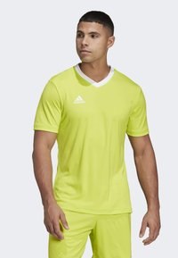 Neon gul atletisk skjorte med V-hals, korte ermer og hvite detaljer. Har Adidas-logoen på venstre bryst. Glatt stoffstruktur.