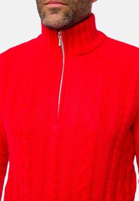 Roter Strickpullover mit hohem Kragen und kurzem Reißverschluss. Verfügt über ein strukturiertes Zopfmuster und gerippte Akzente entlang des Kragens und Saums.
