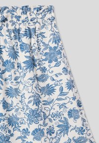 Tessuto a fantasia floreale blu su sfondo bianco, con vita arricciata e intricati motivi di fiori e foglie in tutto il tessuto.