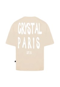 Béžové oversized tričko s kulatým výstřihem a krátkými rukávy. Na přední straně je výrazný bílý text: "CRYSTAL PARIS" a "DEPT.75."