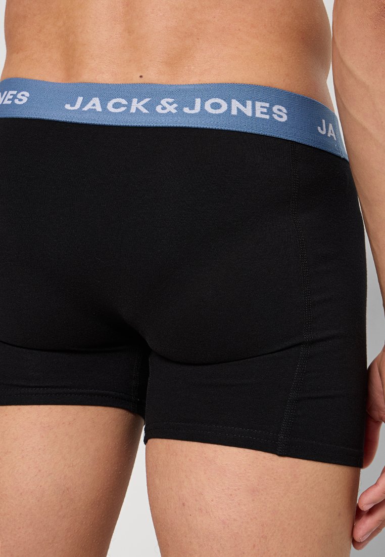 Mustad puuvillased bokserid musta värvi, millel on helesinine elastne vöökoht, millel on valge tähistusega brändi nimi "JACK & JONES". Lähivõte seljapoolt.