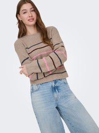 Pull en maille beige avec des rayures horizontales rose, bleu foncé et bordeaux. Doté d'un col rond et d'une coupe décontractée. Associé à un jean bleu clair.