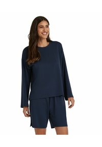 Navyblaues Lounge-Set bestehend aus einem Langarmoberteil und Shorts. Weicher Stoff, lockerer Schnitt, seitliche Schlitz-Details an den Shorts für mehr Bewegungsfreiheit.