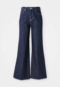 Jeans flared in denim scuro con vita alta, dotati di chiusura a bottone e zip. Le cuciture bianche e le gambe ampie creano una silhouette strutturata.