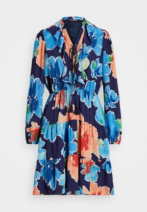 Bloemjurk met een marineblauwe achtergrond, grote blauwe en koraal bloemen, een ruches decolleté en een losvallend, gelaagd ontwerp.